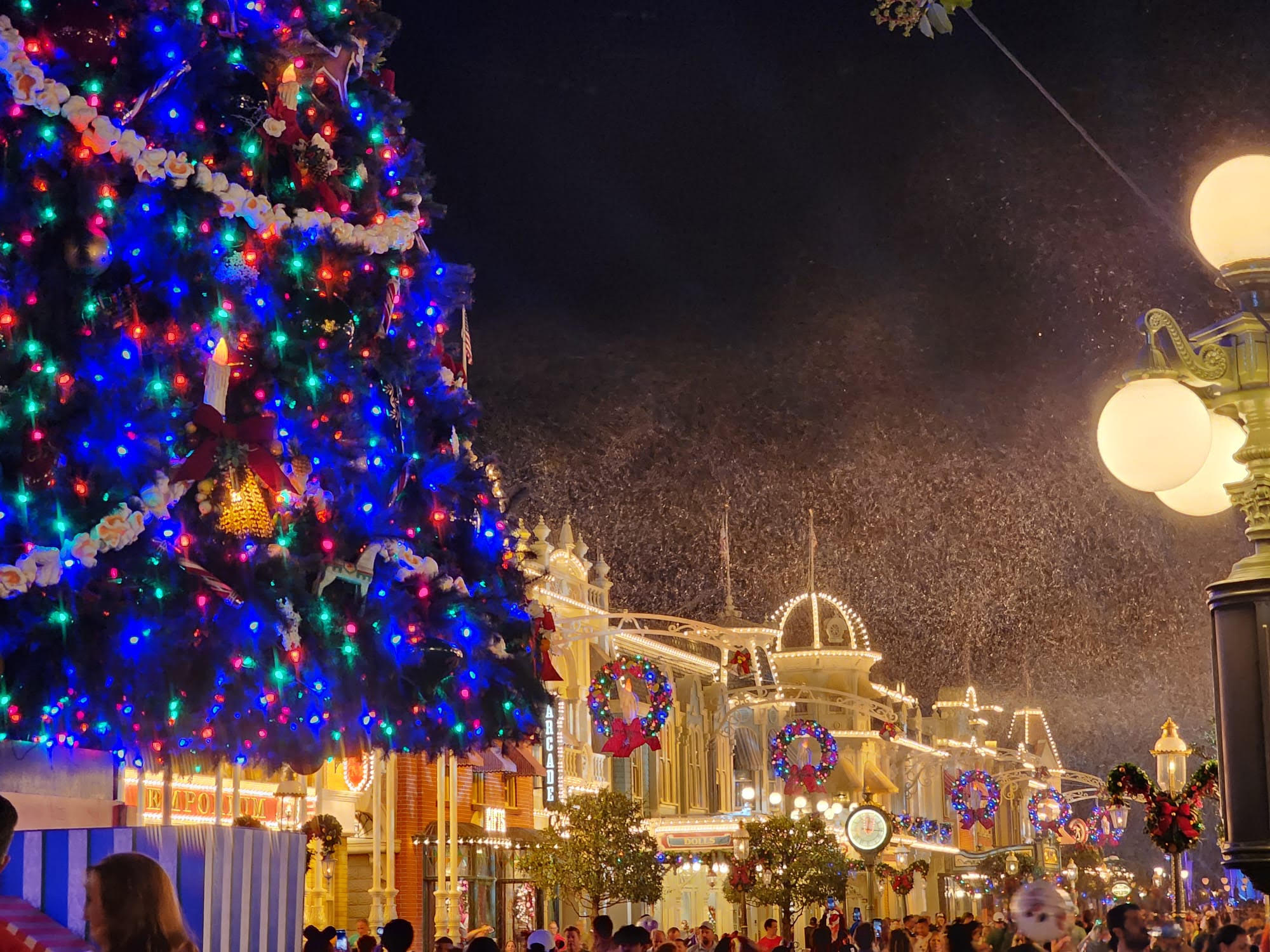 A beautiful nighttime scene looking down Magic Kingdom's Main Street, U.S.A. with holiday decorations and snow.